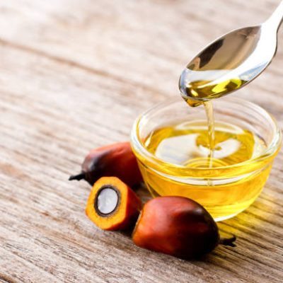 Palm oil in glass bowl and fresh palm fruit on wooden table background.